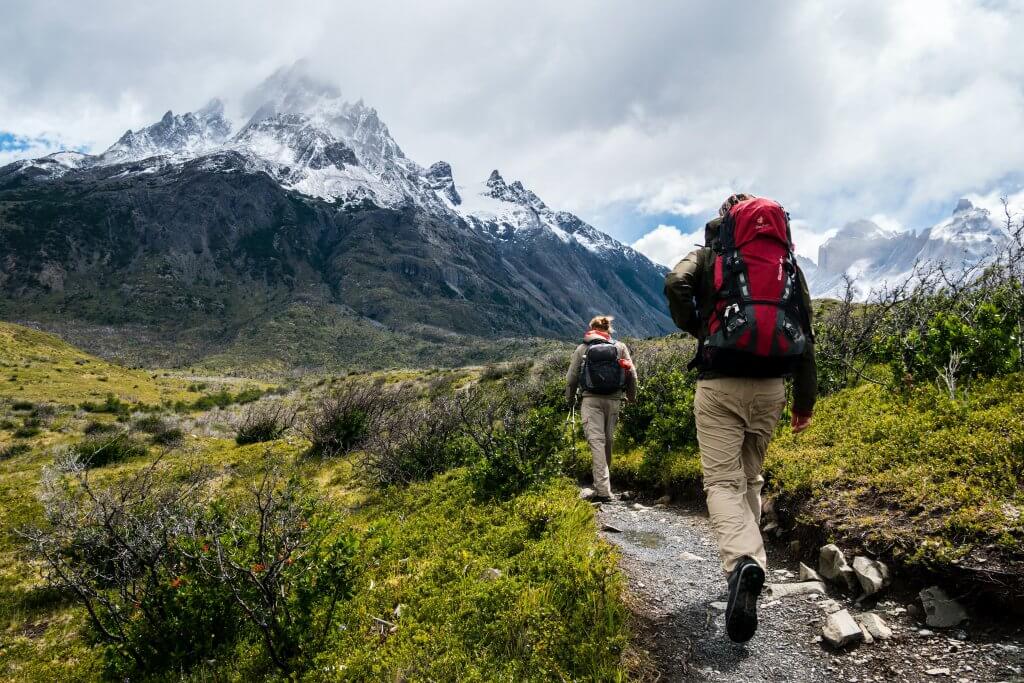 photo from behind of two hikers with mountains in the background