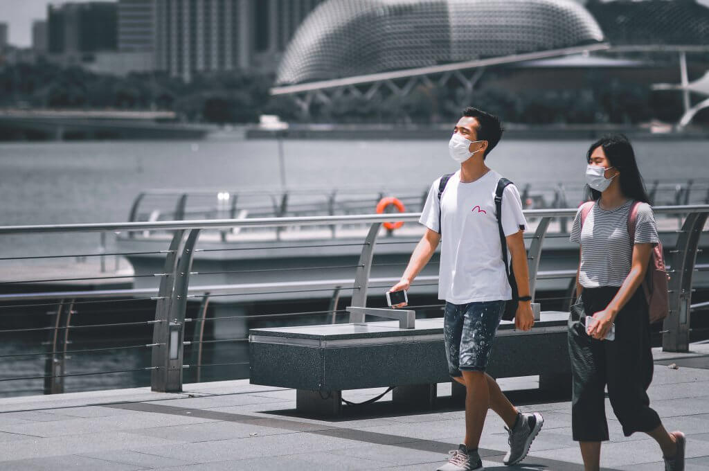 two people walking through singapore while wearing covid masks