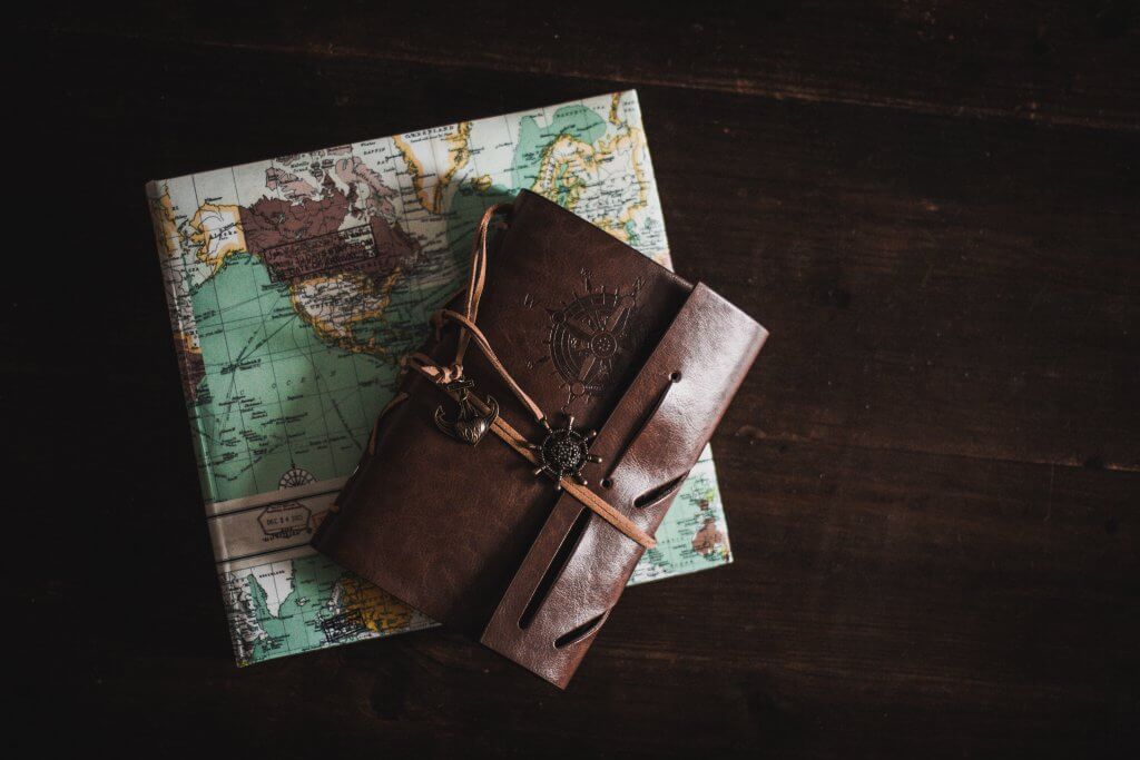 leather travel journal placed over folded map