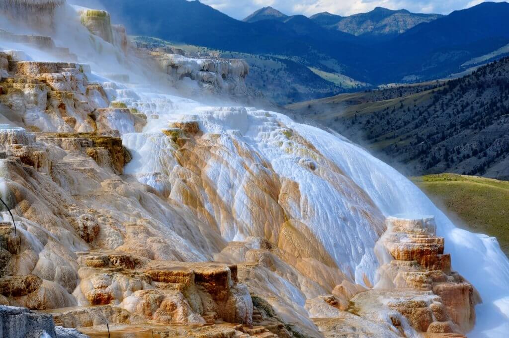 Mammoth hot springs in yellowstone national park with trees and rolling hills in the background