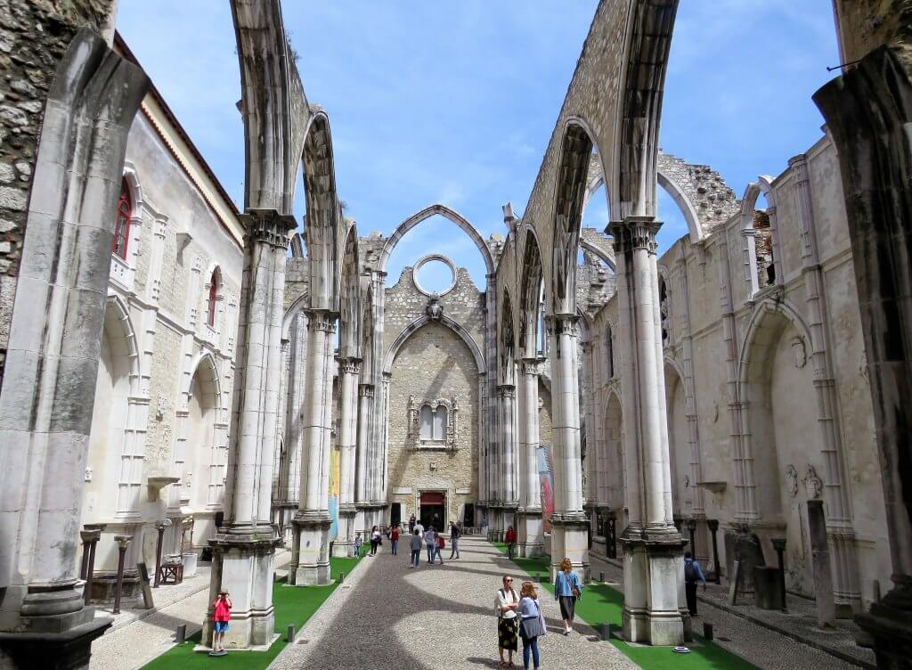 tourists walking through the stone ruins of the carmo convent in lisbon portugal