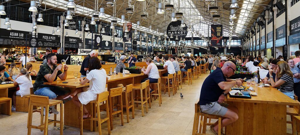 people seated at tables inside of the crowded time out food market