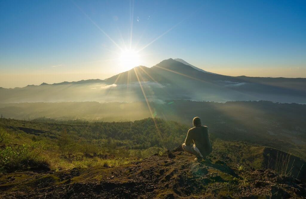 man watching the sun come up behind mountain in Bali