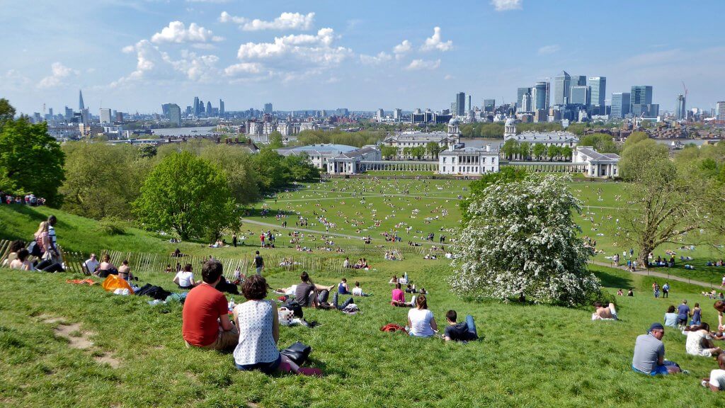 People enjoying a picnic in Greenwich park looking at the London skyline