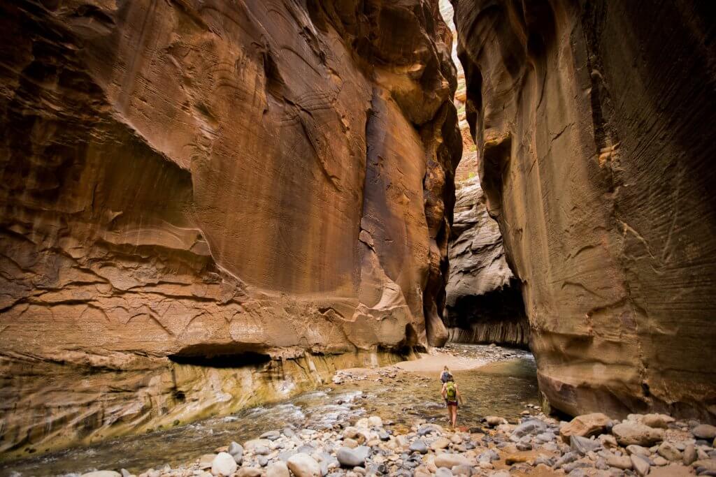 2 people hiking through the narrows in Zion national park