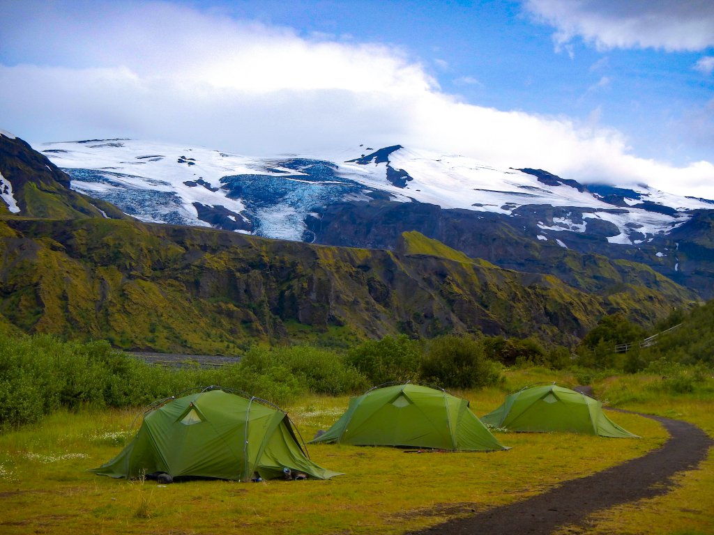 green camping tents against a mountain backdrop
