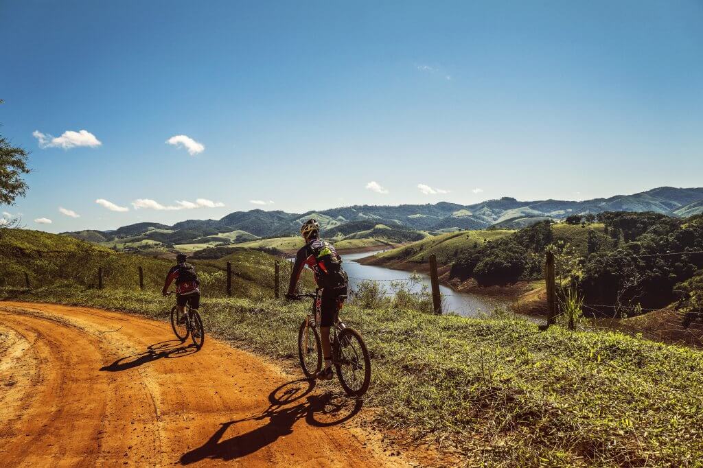 photo from behind of two people riding bicycles on a dirt road