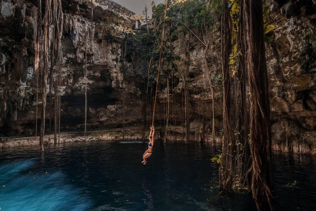 woman on a rope swing at one of Tulum's best cenotes