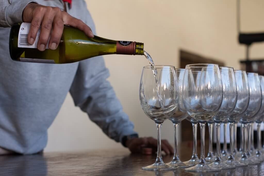 man pouring white wine into glasses at viña undurraga in Chile