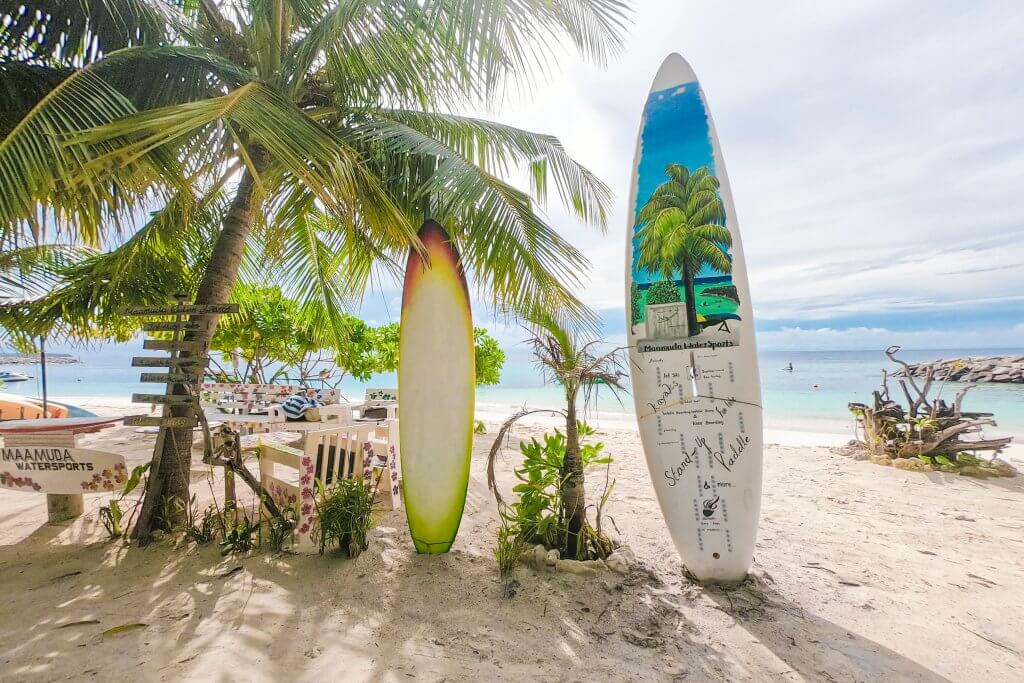 surf boards on a beach advertising prices for rentals in Maafushi, Maldives