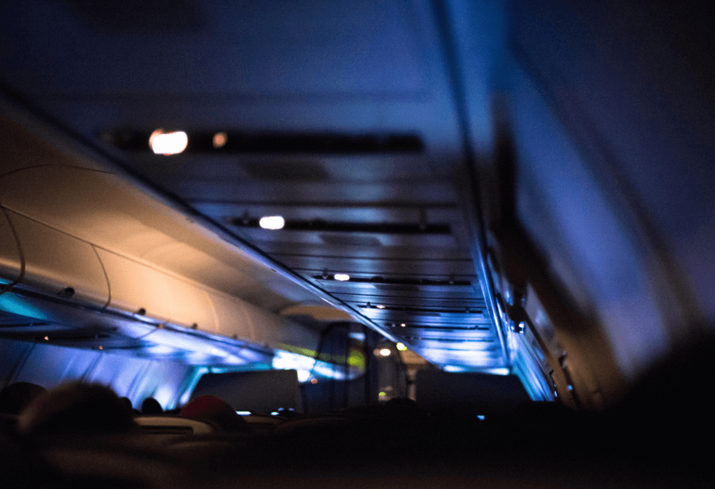 dimmed cabin lights on airplane for article on what is a red eye flight | dollar flight club