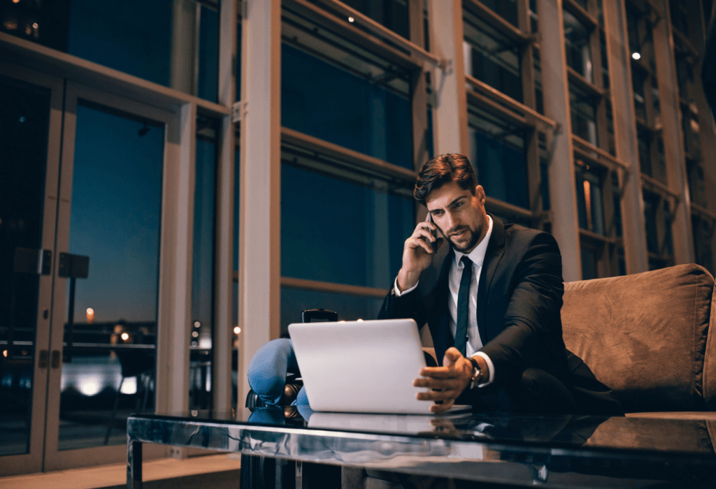 man at airport on laptop at night for article on what is a red eye flight | dollar flight club