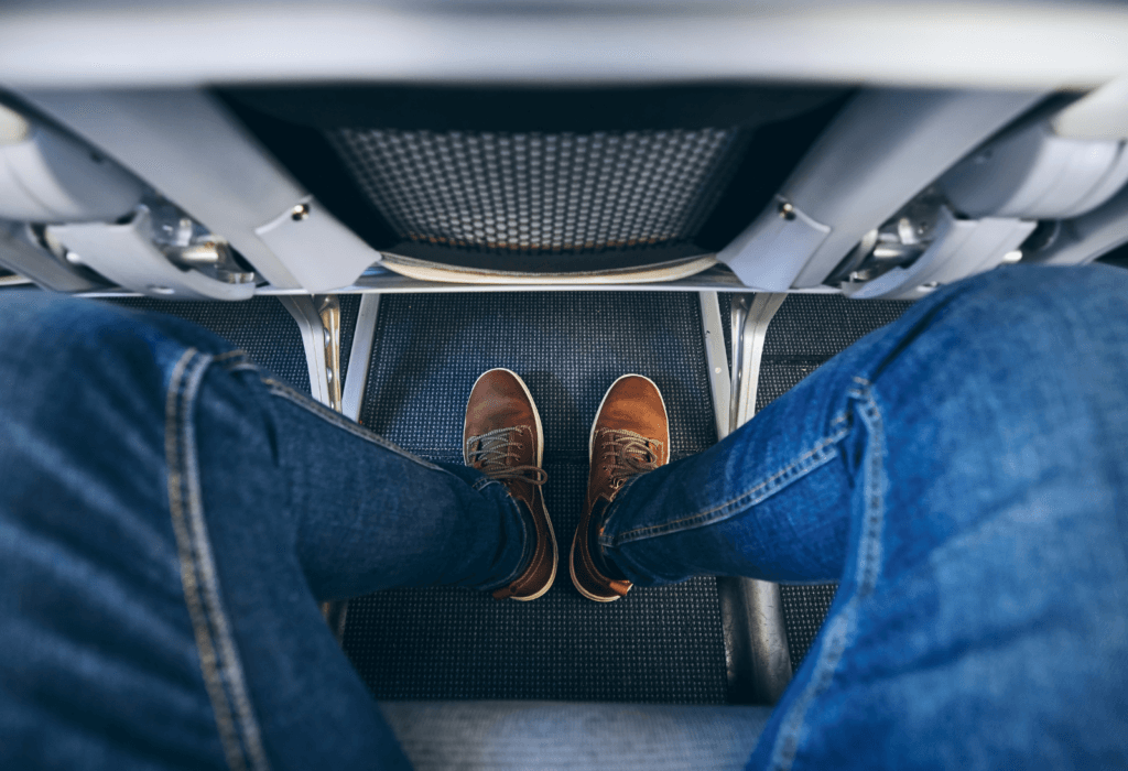 man's legs in plane seat for a guide to the best seats on a plane, and the best airlines for legroom to europe economy