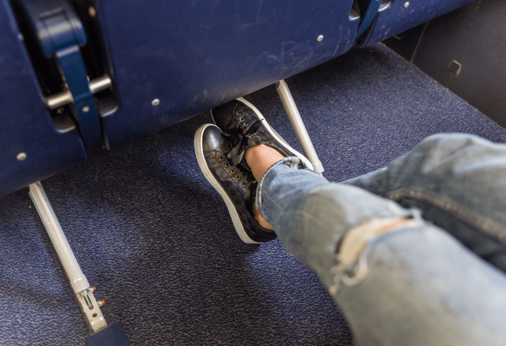 person's legs crossed in an airplane seat for an article that ranks best airlines for legroom to europe economy