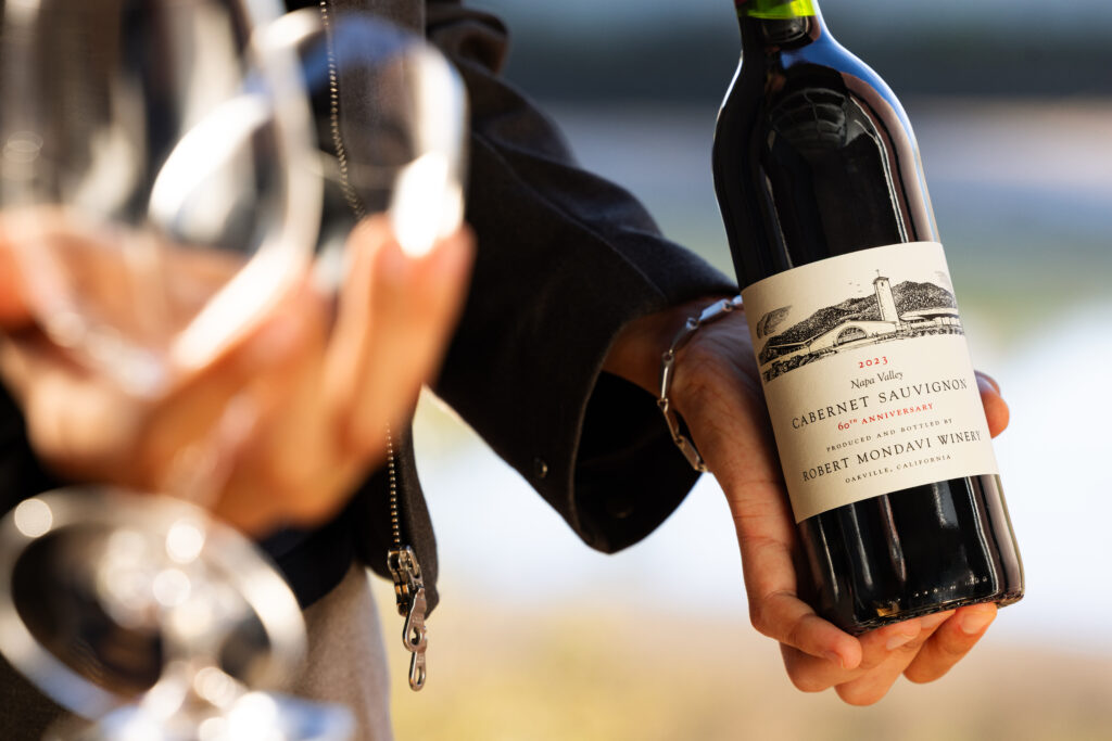 holding Mondavi wine bottles
